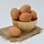 brown eggs on brown wooden bowl on beige knit textile