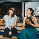 two smiling women sitting on wooden bench