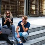 three persons sitting on the stairs talking with each other