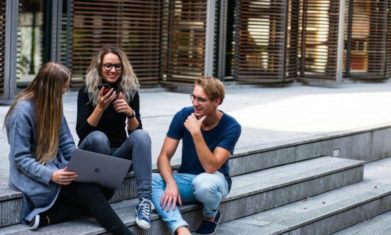 three persons sitting on the stairs talking with each other