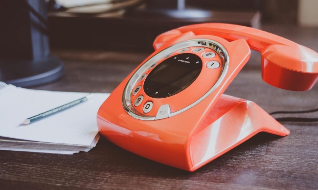 red cradle telephone on brown wooden surface