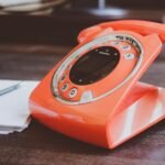 red cradle telephone on brown wooden surface