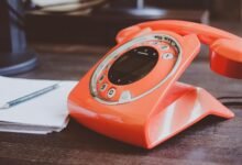 red cradle telephone on brown wooden surface