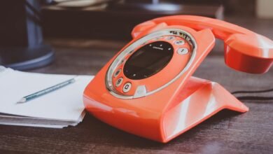 red cradle telephone on brown wooden surface