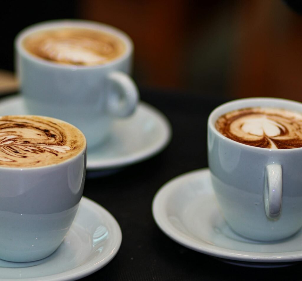 three cups of coffee with different designs on them