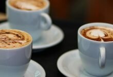 three cups of coffee with different designs on them