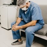 man wearing blue scrub suit and mask sitting on bench