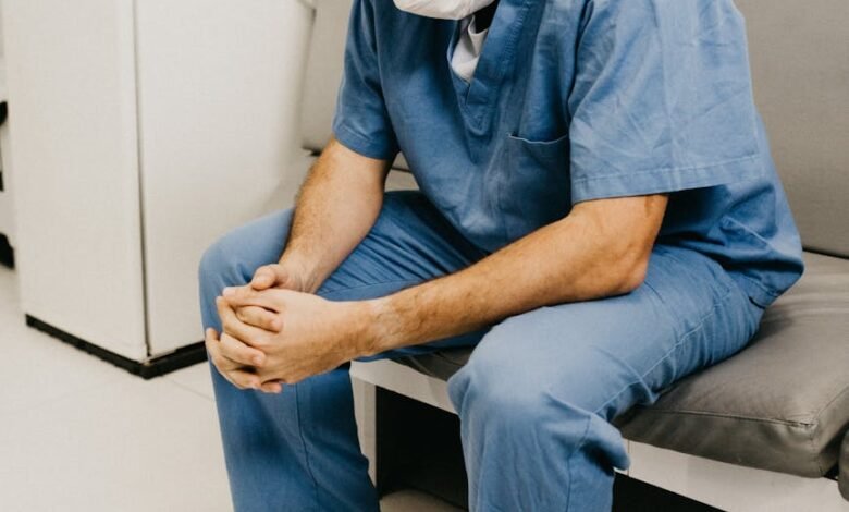 man wearing blue scrub suit and mask sitting on bench