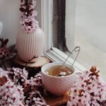 freshly brewed tea in cup among flowers on windowsill