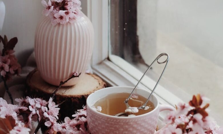 freshly brewed tea in cup among flowers on windowsill