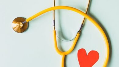 medical stethoscope with red paper heart on white surface