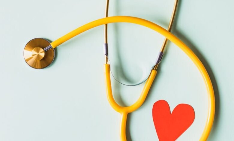 medical stethoscope with red paper heart on white surface