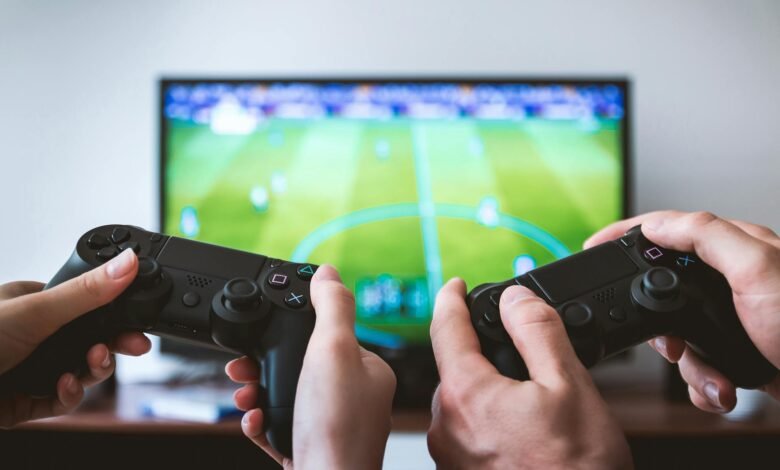 two people holding black gaming consoles