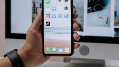 holding a smartphone in front of an imac