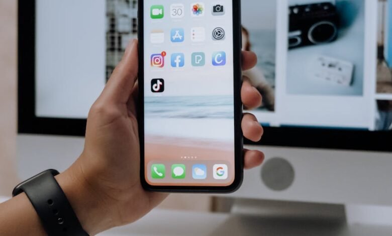 holding a smartphone in front of an imac