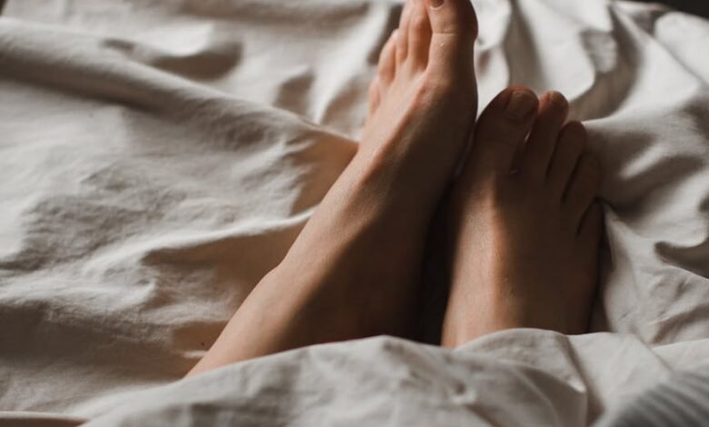 crop unrecognizable female feet lying in cozy bed