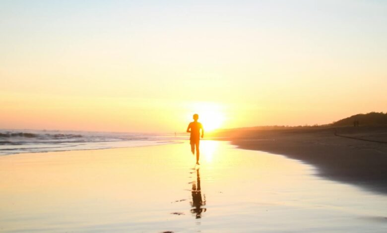 silhouette of boy running in body of water during sunset