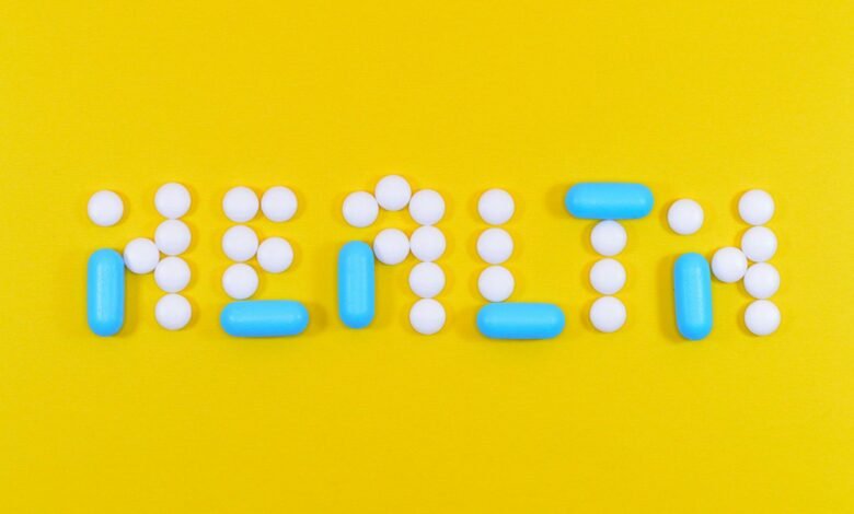 white and blue health pill and tablet letter cutout on yellow surface