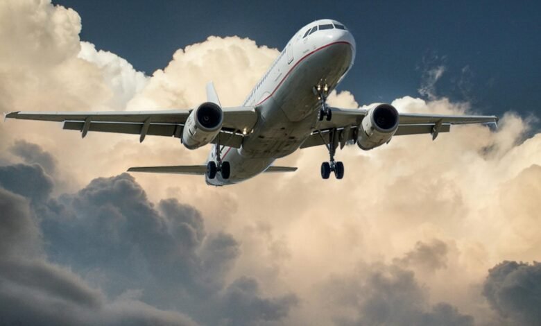 white and red plane beside clouds low angle photography