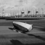 a boat is sitting on the beach in black and white