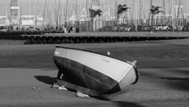 a boat is sitting on the beach in black and white