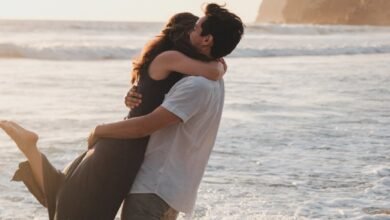 man picking up a woman while standing ankles deep in the sea