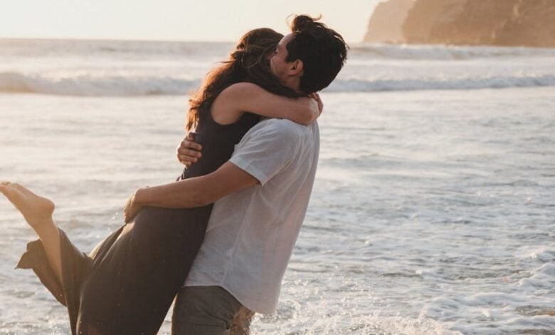 man picking up a woman while standing ankles deep in the sea