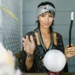 woman in gray headband standing near the crystal ball while smiling at the camera