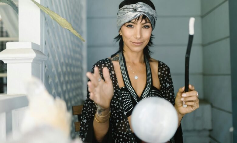 woman in gray headband standing near the crystal ball while smiling at the camera