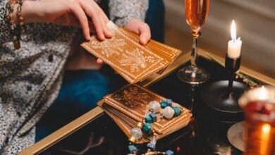 close up of woman holding a deck of tarot cards and sitting at a table with champagne glasses