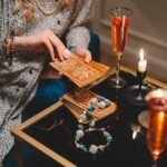 close up of woman holding a deck of tarot cards and sitting at a table with champagne glasses