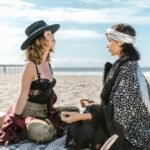 two women sitting on the beach